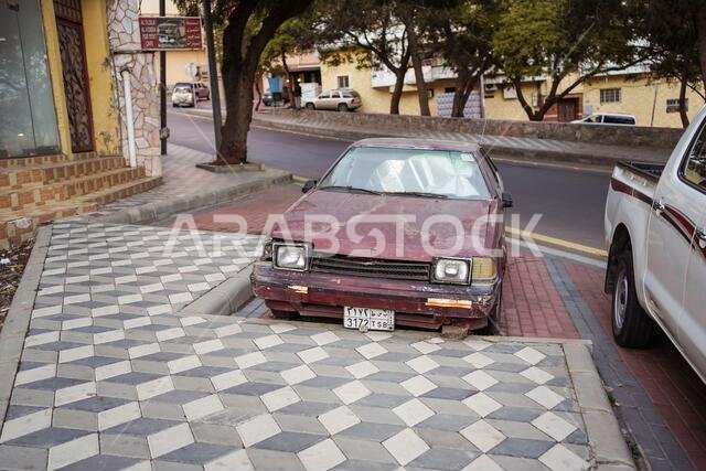 Abha / Saudi Arabia - January 23, 2020: old and rusty red car parked on the street