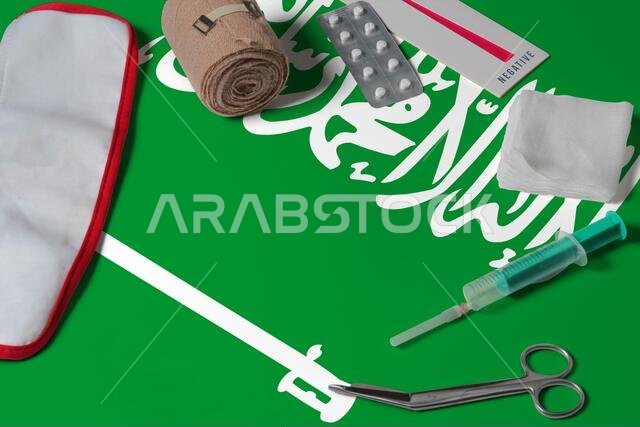 علم المملكة العربية السعودية مع حقيبة إسعافات أولية على خلفية طاولة خشبية. مفهوم النظام الصحي الوطني، موضوع طبي. علم المملكة العربية السعودية مع حقيبة إسعافات أولية على خلفية طاولة خشبية. مفهوم النظام الصحي الوطني، موضوع طبي.