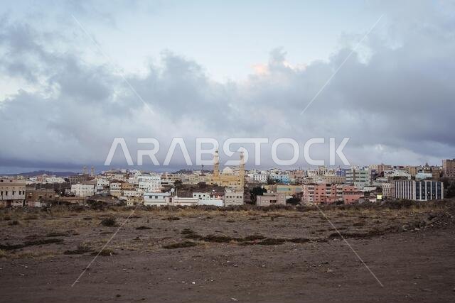 Abha / Saudi Arabia - January 23, 2020: panorama cityscape view of Abha and mosque with minarets against cloudy sky during sunset