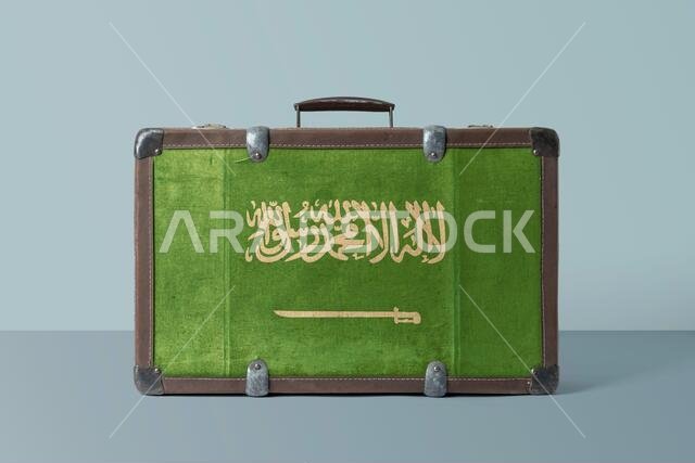 علم المملكة العربية السعودية على حقيبة سفر جلدية عتيقة الطراز تحمل رمزاً وطنياً. حقيبة سفر بنية اللون بتصميم كلاسيكي مع مساحة للكتابة.