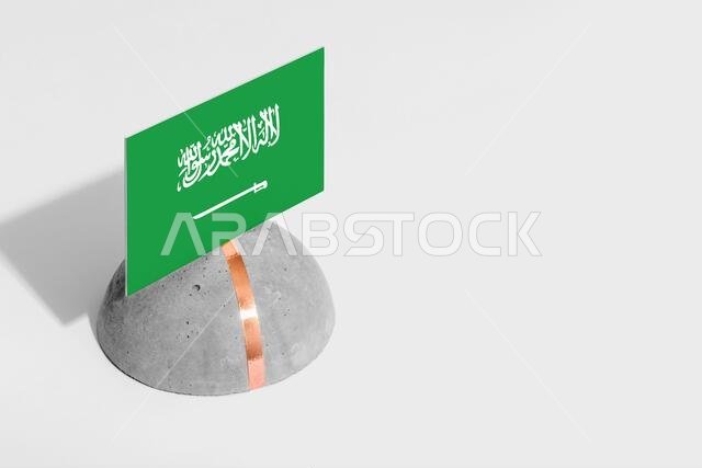 علم المملكة العربية السعودية محفور على حجر مستدير. خلفية بيضاء معزولة. منظر جانبي لمفهوم وطني بسيط.