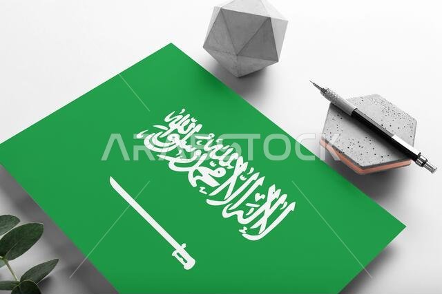 Saudi Arabia flag on minimalist paper background. National invitation letter with stylish pen on stone. Communication concept.