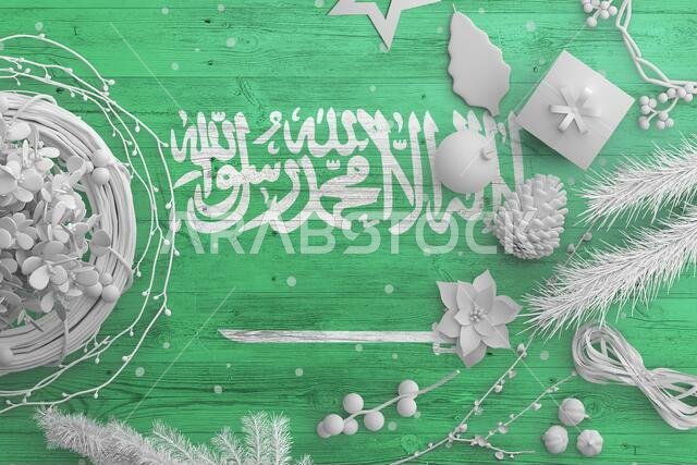 Saudi Arabia flag on wooden table with snow objects. Christmas and new year background, celebration national concept with white decor.