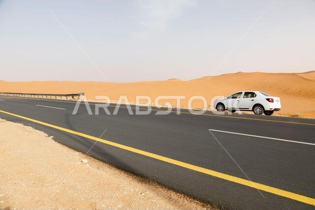 Riad, Saudi Arabia, February 16 2020: Typical road in Saudi Arabia that leads through the desert. There is a white car on the road bike.
