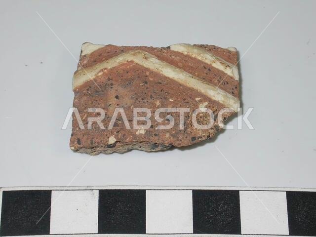 شظية صغيرة من طين خشن جدًا (تحتوي على العديد من الشوائب السوداء والبيضاء والرمادية). شرائط من الطين الأبيض بنمط متعرج كزخرفة. أوانٍ فخارية، متوسط السماكة: 0.7 سم، المملكة العربية السعودية