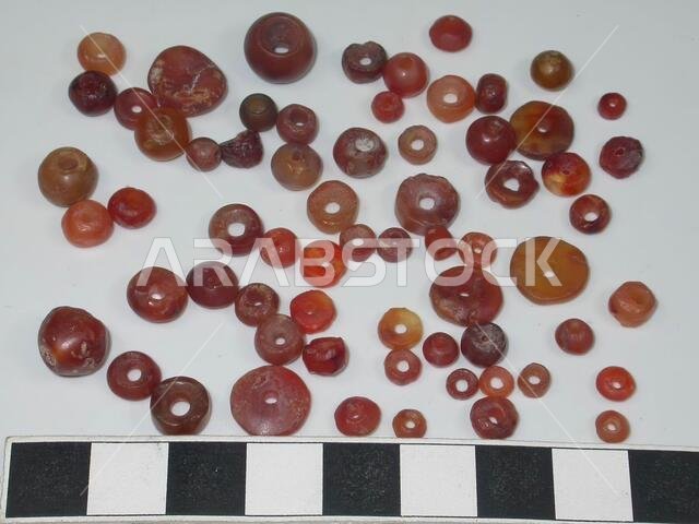 65 round, red beads, varying in size and shape (some are flat, others around)., Ornament, stone, cornaline, largest: D 1.1 cm., Smallest: D 0.4 cm., Saudi Arabia