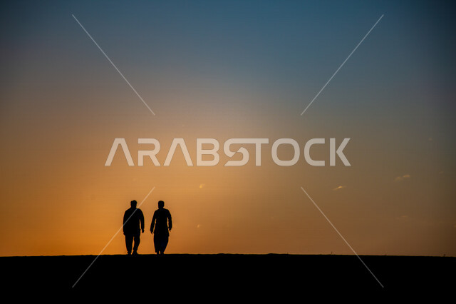 Silhouette of two men walking in the desert areas of Saudi Arabia, silhouette at sunset, Saudi deserts, desert areas