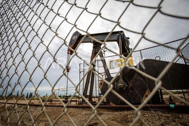 Oil Pump in Cloudy Rough Weather with Chain Link Fence