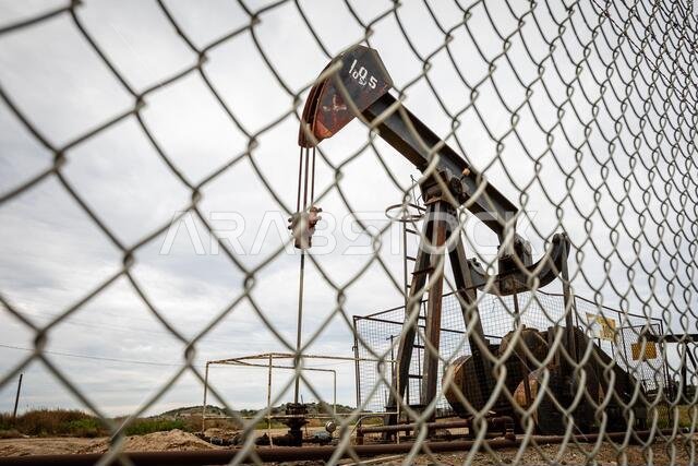 Oil Pump in Cloudy Rough Weather with Chain Link Fence