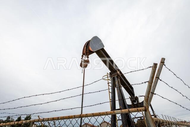 Oil Pump in Cloudy Rough Weather with Chain Link Fence