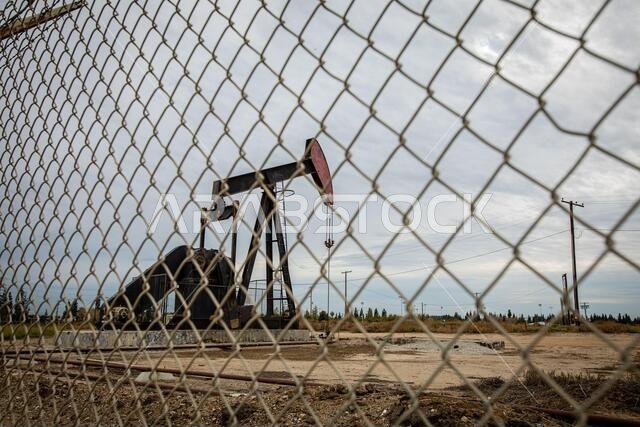 Oil Pump in Cloudy Rough Weather with Chain Link Fence