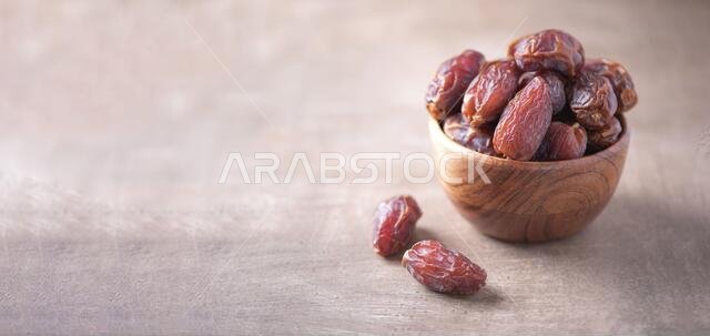 Dried date fruit in wooden bowl on wood textured background. Copy space. Superfood, vegan, vegetarian food concept. Macro of dates texture, selective