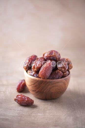 Dried date fruit in wooden bowl on wood textured background. Copy space. Superfood, vegan, vegetarian food concept. Macro of dates texture, selective