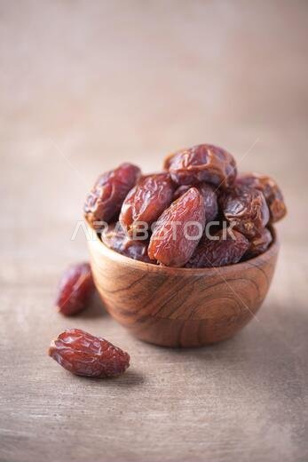 Dried date fruit in wooden bowl on wood textured background. Copy space. Superfood, vegan, vegetarian food concept. Macro of dates texture, selective