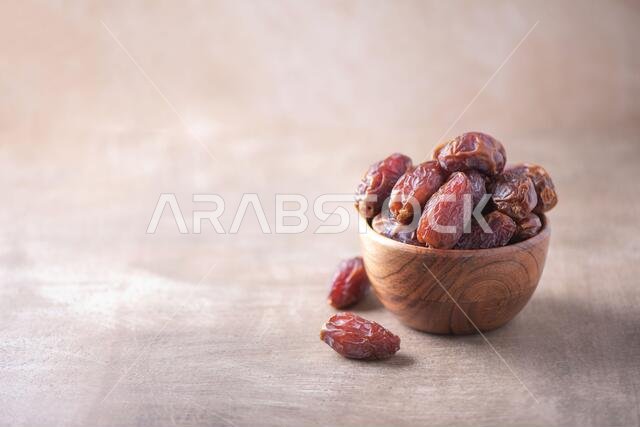 Dried date fruit in wooden bowl on wood textured background. Copy space. Superfood, vegan, vegetarian food concept. Macro of dates texture, selective