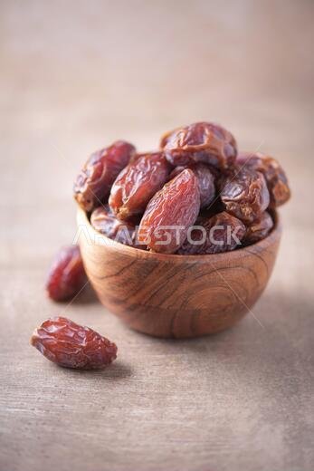 Dried date fruit in wooden bowl on wood textured background. Copy space. Superfood, vegan, vegetarian food concept. Macro of dates texture, selective