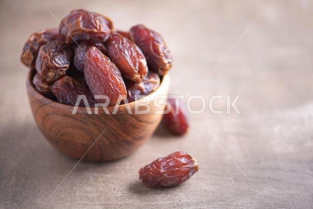 Dried date fruit in wooden bowl on wood textured background. Copy space. Superfood, vegan, vegetarian food concept. Macro of dates texture, selective