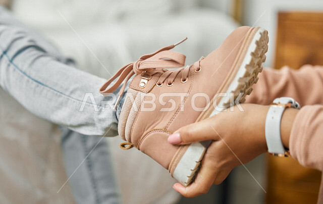 Close-up of a mother taking care of her child, helping the child get dressed, putting on new clothes, getting ready for school, putting on shoes