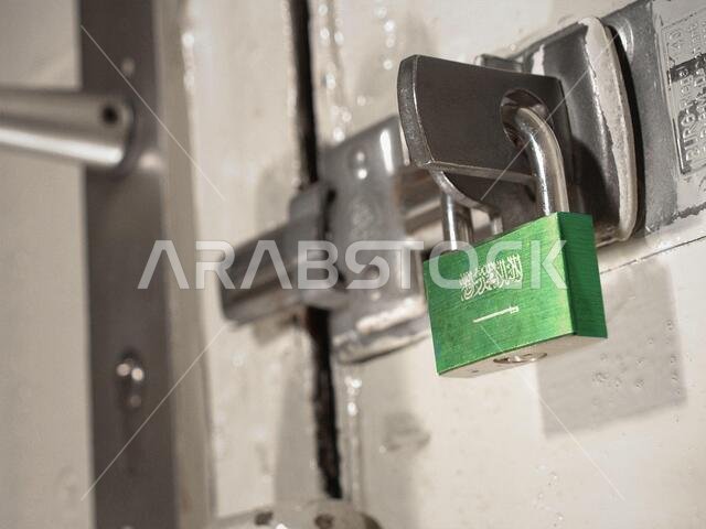باب مقفل بقفل عليه علم المملكة العربية السعودية. (سلسلة)