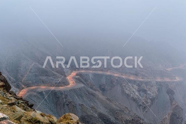 Long exposure of car light trails on a foggy mountain road at Al Huda, Saudi Arabia