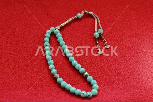 turquoise color praying beads on red background