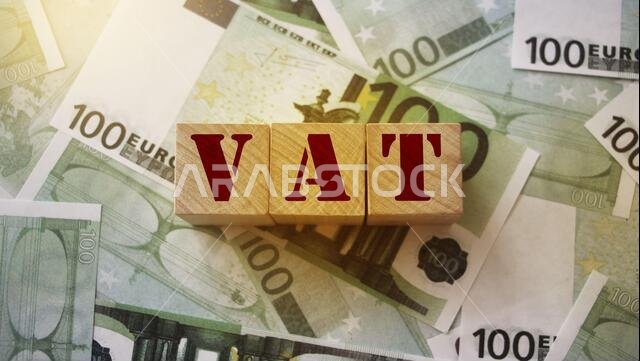 VAT on wooden alphabet cubes with 100 euro banknotes around. Selective focus . Taxes and fees financial concept