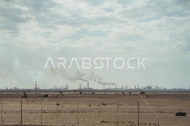 Oil refinery with smokestacks fuming seen from afar in Saudi Arabia
