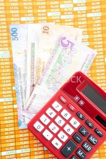 Red Calculator on a spreadsheet with Saudi Riyal Notes
