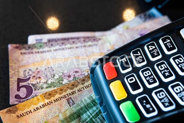 جهاز دفع إلكتروني ببطاقات الائتمان مع أوراق نقدية من الريال السعودي