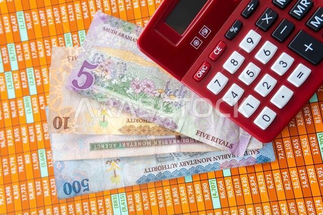 Red Calculator on a spreadsheet with Saudi Riyal Notes