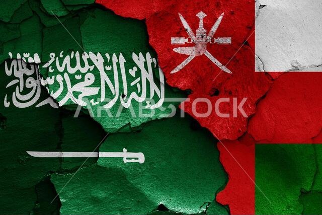 flags of Saudi Arabia and Oman painted on cracked wall