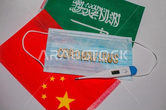 مفهوم تفشي فيروس كورونا المستجد. قناع تنفس واقٍ من فيروس كورونا وحقنة فوق العلم الصيني وعلم المملكة العربية السعودية. 2019-nCoV