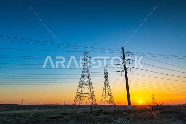 برج كهرباء ذو جهد عالٍ عند شروق الشمس، والسماء على خلفية شروق الشمس. طريق الجبيل السريع - المملكة العربية السعودية.