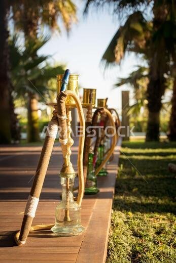 Hookah, traditional arabic waterpipe, in the arabic restaurant. Vertical, direct sunset light, outdoor photo