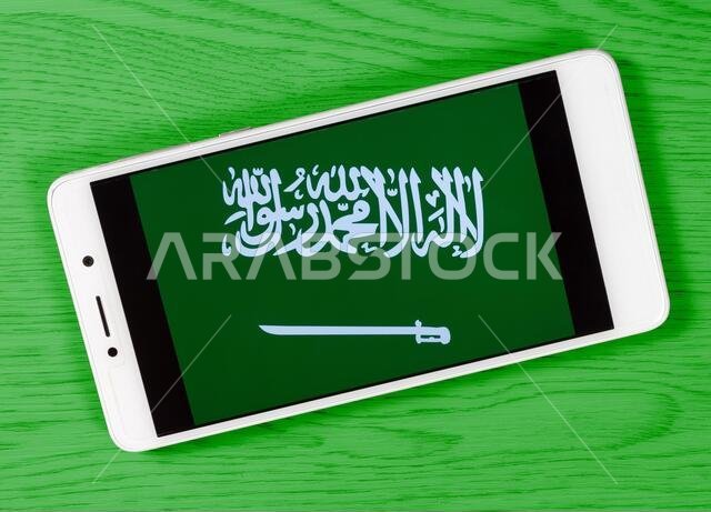 Flag of Saudi Arabia composed by placing a smartphone displaying its symbol on a colored wooden background