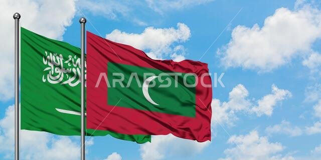 Saudi Arabia and Maldives flag waving in the wind against white cloudy blue sky together. Diplomacy concept, international relations.