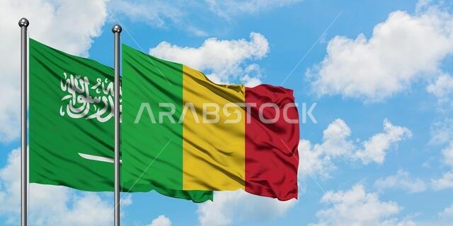 Saudi Arabia and Mali flag waving in the wind against white cloudy blue sky together. Diplomacy concept, international relations.