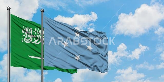 يرفرف علم المملكة العربية السعودية وعلم ميكرونيزيا معاً في مهب الريح أمام سماء زرقاء صافية تتلألأ بالغيوم البيضاء. مفهوم الدبلوماسية، العلاقات الدولية.