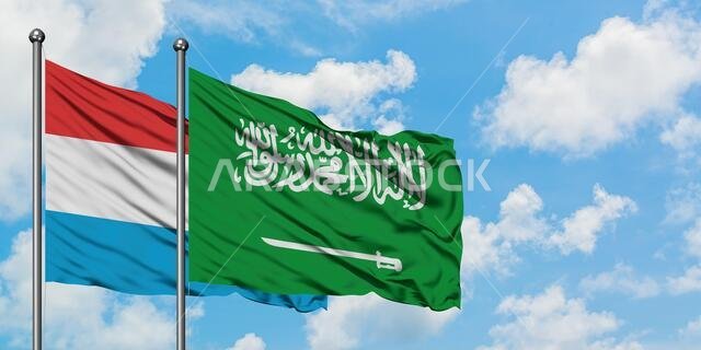 يرفرف علم لوكسمبورغ وعلم المملكة العربية السعودية معاً في مهب الريح أمام سماء زرقاء صافية تتلألأ بالغيوم البيضاء. مفهوم الدبلوماسية، العلاقات الدولية.