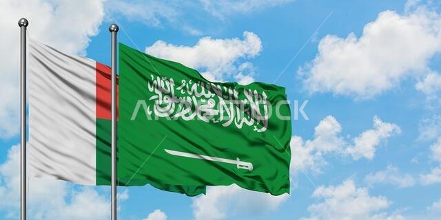 Madagascar and Saudi Arabia flag waving in the wind against white cloudy blue sky together. Diplomacy concept, international relations.