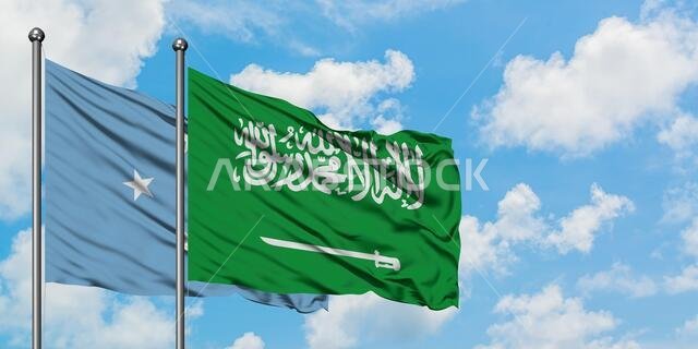 يرفرف علم ميكرونيزيا وعلم المملكة العربية السعودية معاً في مهب الريح أمام سماء زرقاء ملبدة بالغيوم البيضاء. مفهوم الدبلوماسية، العلاقات الدولية.