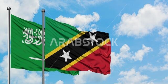 Saudi Arabia and Saint Kitts And Nevis flag waving in the wind against white cloudy blue sky together. Diplomacy concept, international relations.