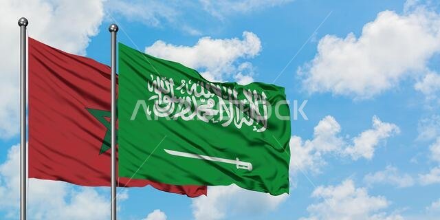 يرفرف علم المغرب والسعودية معاً في مهب الريح أمام سماء زرقاء صافية تتخللها غيوم بيضاء. مفهوم الدبلوماسية، العلاقات الدولية.