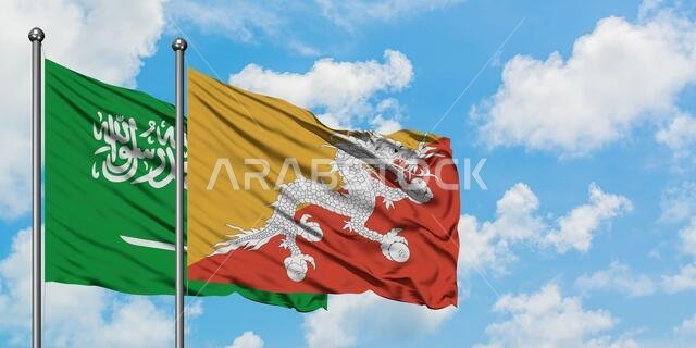 يرفرف علم المملكة العربية السعودية وعلم بوتان معاً في مهب الريح أمام سماء زرقاء صافية تتخللها غيوم بيضاء. مفهوم الدبلوماسية، العلاقات الدولية.
