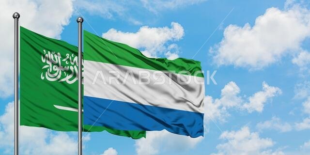 يرفرف علم المملكة العربية السعودية وعلم سيراليون معاً في مهب الريح أمام سماء زرقاء صافية تتلألأ فيها الغيوم البيضاء. مفهوم الدبلوماسية، العلاقات الدولية.