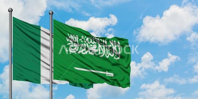 يرفرف علم نيجيريا وعلم السعودية معاً في مهب الريح أمام سماء زرقاء صافية تتخللها غيوم بيضاء. مفهوم الدبلوماسية، العلاقات الدولية.
