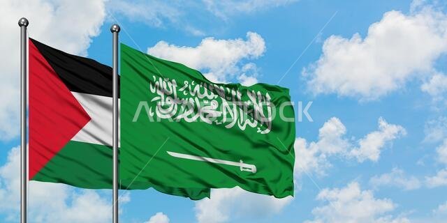 يرفرف علم فلسطين وعلم السعودية معاً في مهب الريح أمام سماء زرقاء صافية تتلألأ بالغيوم البيضاء. مفهوم الدبلوماسية، العلاقات الدولية.