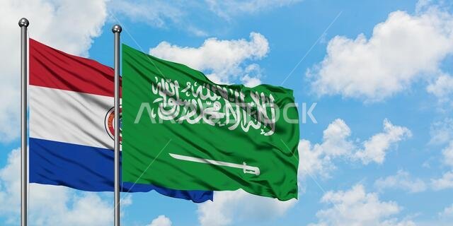 يرفرف علم باراغواي وعلم المملكة العربية السعودية معاً في مهب الريح أمام سماء زرقاء صافية تتخللها غيوم بيضاء. مفهوم الدبلوماسية، العلاقات الدولية.