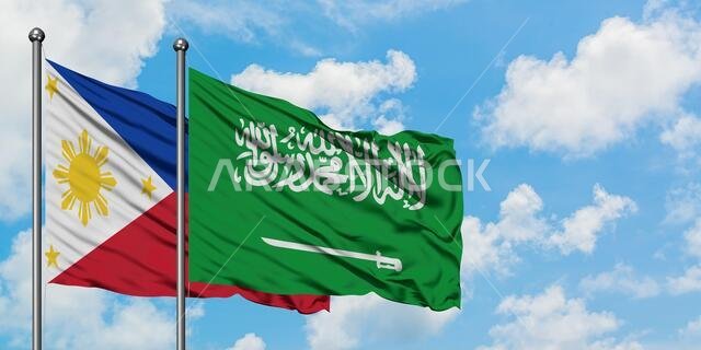 يرفرف علم الفلبين وعلم المملكة العربية السعودية معاً في مهب الريح أمام سماء زرقاء صافية تتخللها غيوم بيضاء. مفهوم الدبلوماسية، العلاقات الدولية.