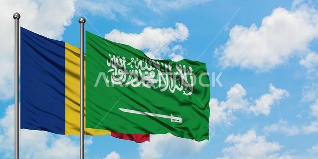 يرفرف علم رومانيا والسعودية معاً في مهب الريح أمام سماء زرقاء صافية تتلألأ بالغيوم البيضاء. مفهوم الدبلوماسية، العلاقات الدولية.